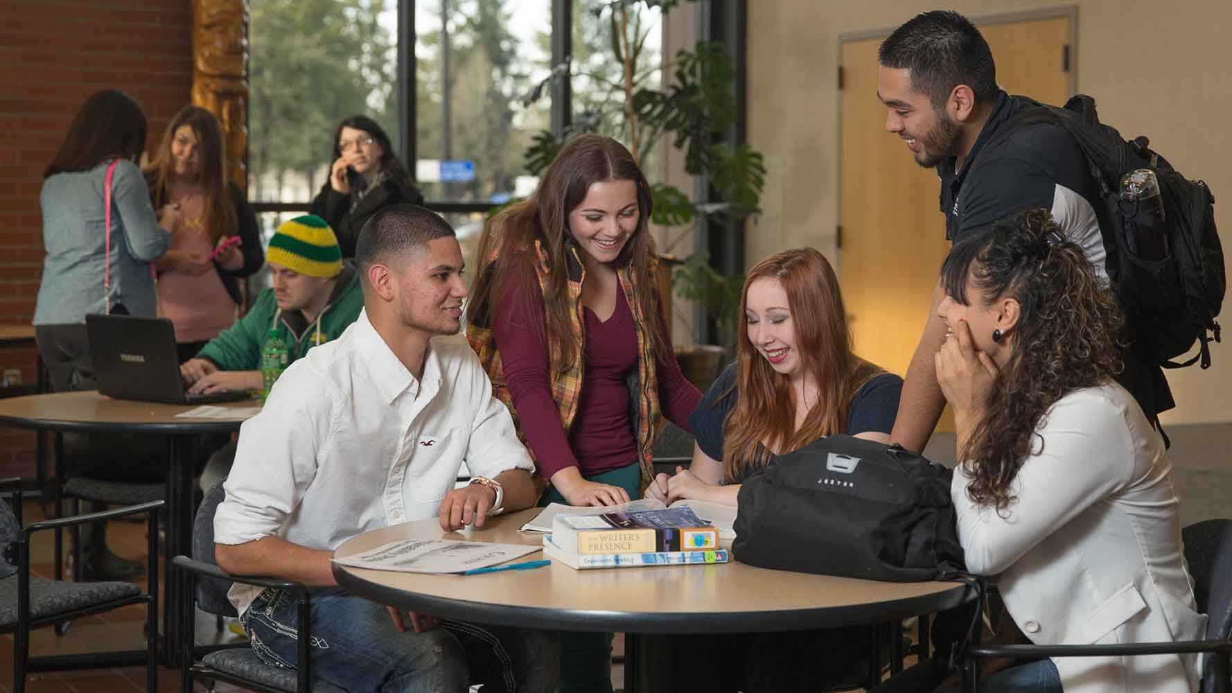 The members of a study group laugh as they study a textbook